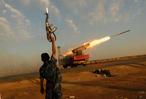 A-rebel-fighter-celebrates-as-his-comrades-fire-a-rocket-barrage-toward-the-positions-of-government-troops-on-April-14,-2011-west-of-Ajdabiyah,-Libya.