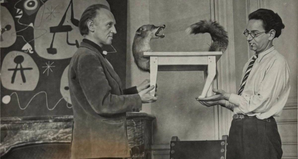 Victor Brauner, în fața unui tablou de Joan Miró, prezentându-și sculptura Lupul-masă (1939-1947)